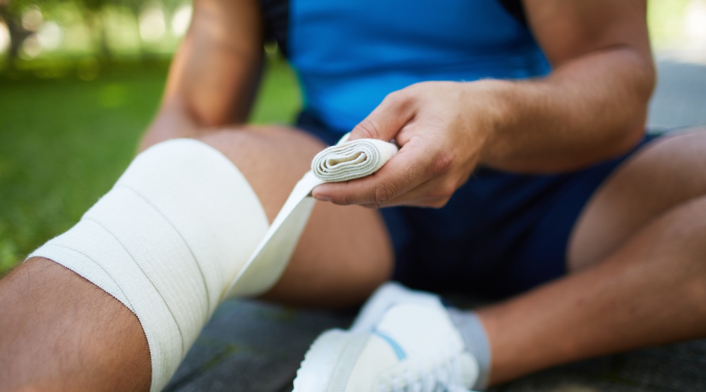 Kompressionstrümpfe / Bandagen Jemand wickelt sich einen Verband um das Bein